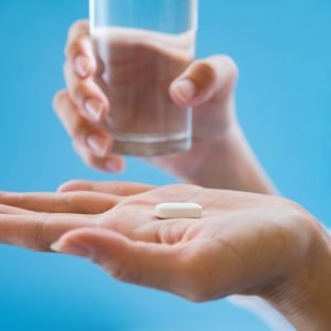 Woman's hand pours the medicine pills out of the bottle